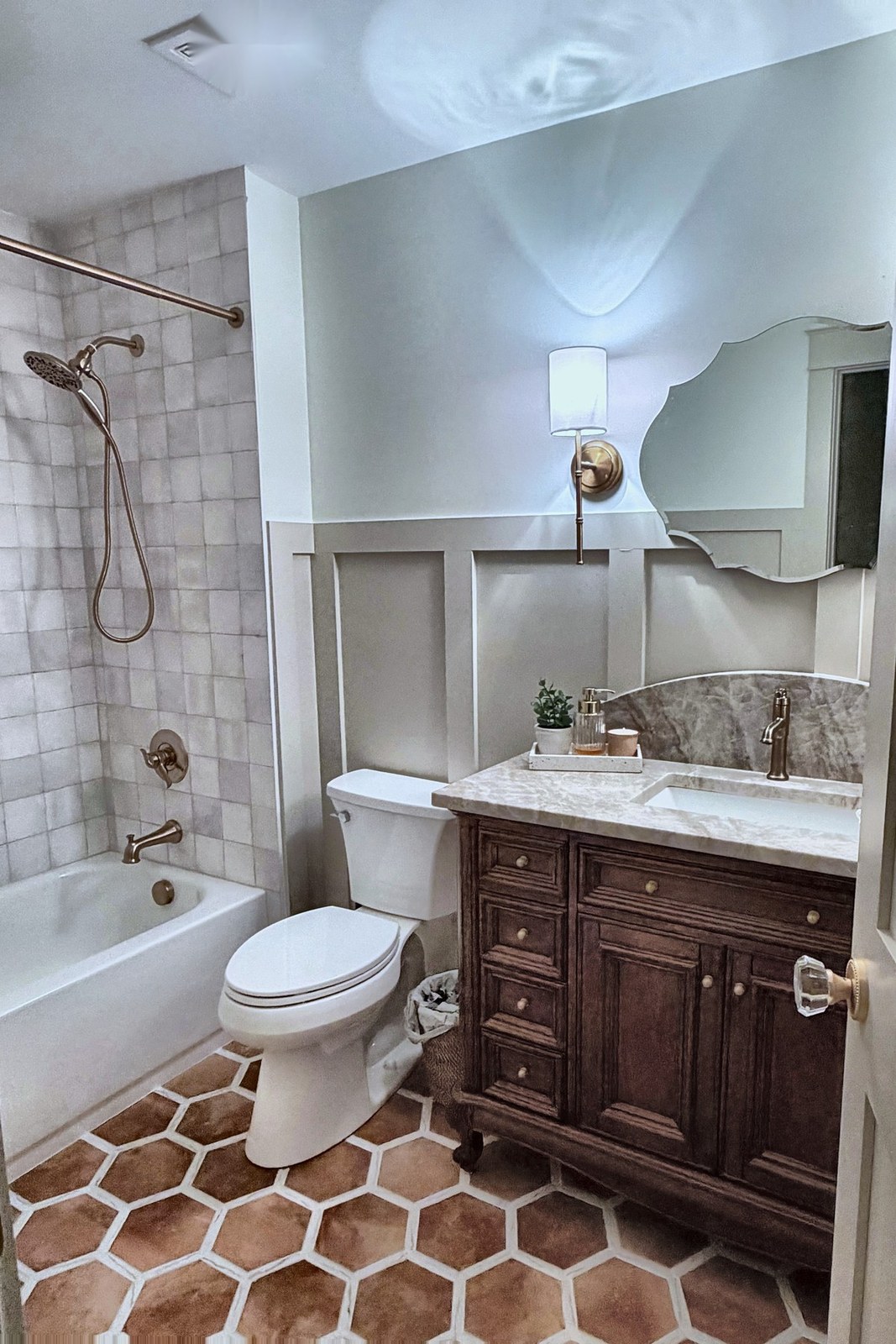 Bathroom with wood vanity, brass fixtures, and terracotta hex tile
